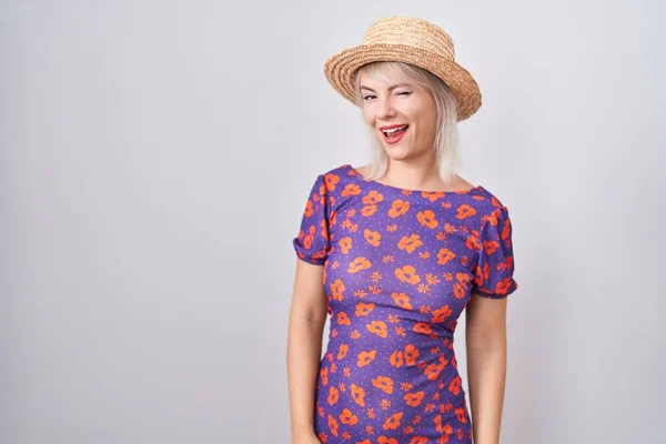 年轻的高加索女人穿着花衣服 头戴夏帽 看着相机 脸上带着性感的表情 笑容满面 喜形于色 — 图库照片
