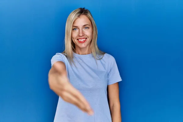 Piękna Blondynka Ubrana Luźną Koszulkę Niebieskim Tle Uśmiechnięta Przyjazna Oferująca — Zdjęcie stockowe