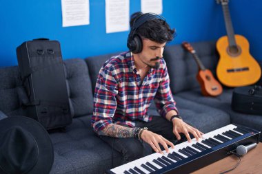 Genç İspanyol müzisyen müzik stüdyosunda piyano çalıyor.