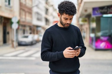 Sokakta akıllı telefon kullanan genç bir Arap.