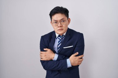 Genç Asyalı takım elbiseli ve kravatlı adam kış soğuğu için titriyor ve donuyor. Yüzünde üzgün ve şok ifadesi var. 