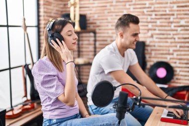 Erkek ve kadın müzisyenler müzik stüdyosunda beste yapıyorlar.