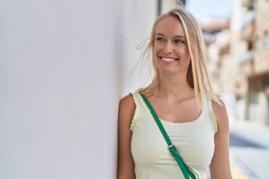 Young blonde woman smiling confident looking to the side at street