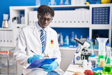 Afrikalı Amerikalı bilim adamı laboratuarda rapor yazıyor.
