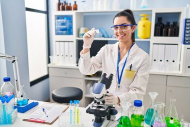 Genç ve güzel İspanyol bilim kadını laboratuarda mikroskop numunesi kullanıyor.