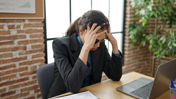 Молодая красивая латиноамериканка бизнес-работница подчеркнул, используя ноутбук в офисе