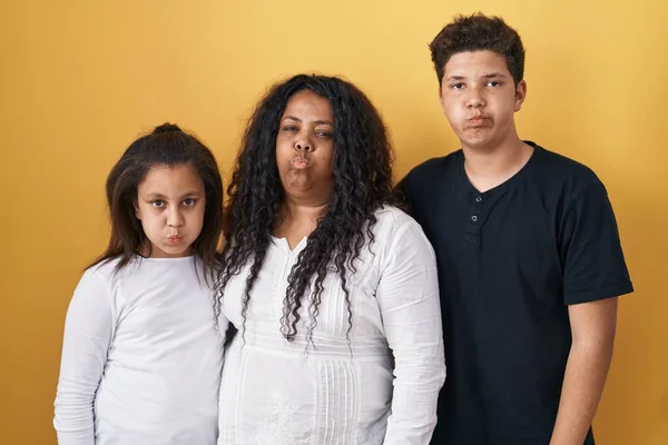 女儿和儿子的家人站在黄色的背景上 两颊通红 气喘吁吁的嘴 疯狂的表情 — 图库照片