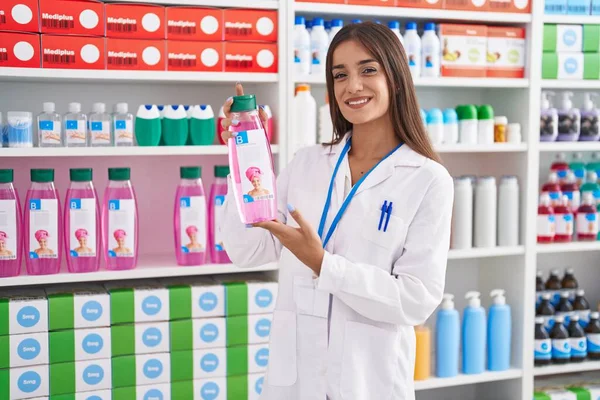 Young Beautiful Hispanic Woman Pharmacist Holding Shampoo Bottle Pharmacy — 图库照片
