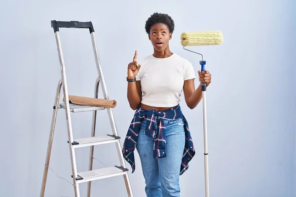 Africano Americano Mulher Segurando Pintor Rolos Espantado Surpreso Olhando Para — Fotografia de Stock