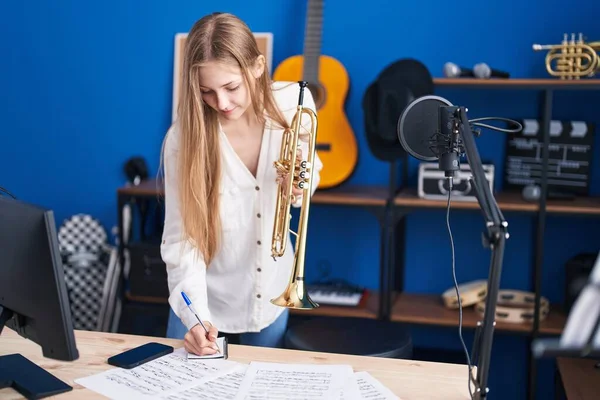 Young Caucasian Woman Musician Composing Song Holding Trumpet Music Studio — Stockfoto