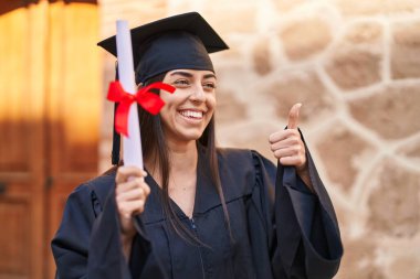 Mezuniyet üniforması giyen genç İspanyol kadın üniversitede el kol hareketi yapıyor.