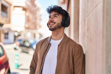 Sokakta müzik dinlerken kendinden emin gülümseyen İspanyol genç adam.