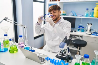 Laboratuvarda çalışan genç Arap bilim adamı dizüstü bilgisayar kullanıyor.