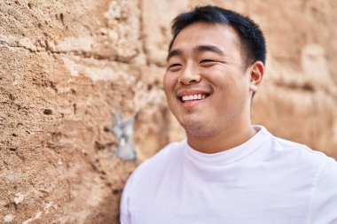 Young chinese man smiling confident standing at street