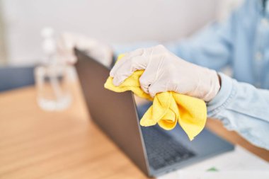 Young hispanic man business worker cleaning laptop at office