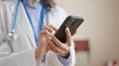 Klinikte akıllı telefon kullanan genç, güzel İspanyol kadın doktor.