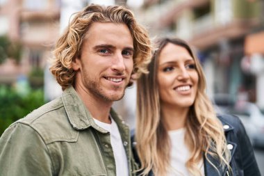 Erkek ve kadın bir arada durarak gülümsüyor.