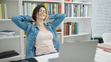 Kafkasyalı genç bir kız öğrenci üniversite sınıfında rahatça ders çalışıyor.