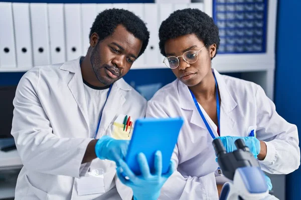 アフリカ系アメリカ人の男性と女性科学者が実験室でタッチパッドを使って — ストック写真