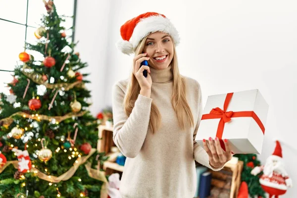 Junge Blonde Frau Spricht Auf Dem Smartphone Und Hält Weihnachtsgeschenk — Stockfoto