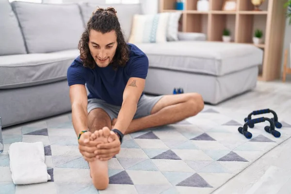 Young Hispanic Man Stretching Leg Sitting Floor Home — Fotografia de Stock