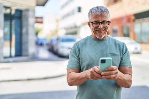 中年白发男子在街上用智能手机自信地微笑 — 图库照片