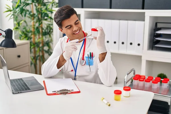 Young Hispanic Man Doctor Writing Medical Report Holding Urine Test — Foto de Stock