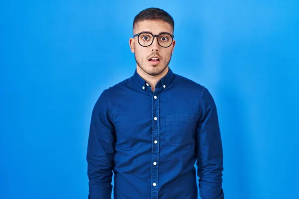 Jovem Hispânico Vestindo Óculos Sobre Fundo Azul Com Medo Chocado — Fotografia de Stock