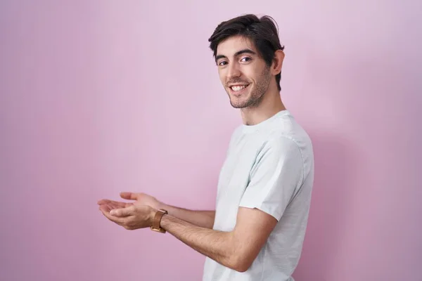 Jonge Spaanse Man Staat Roze Achtergrond Wijzen Opzij Met Handen — Stockfoto
