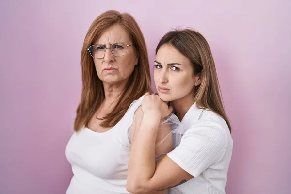 Hispanic mother and daughter wearing casual white t shirt skeptic and nervous, frowning upset because of problem. negative person.