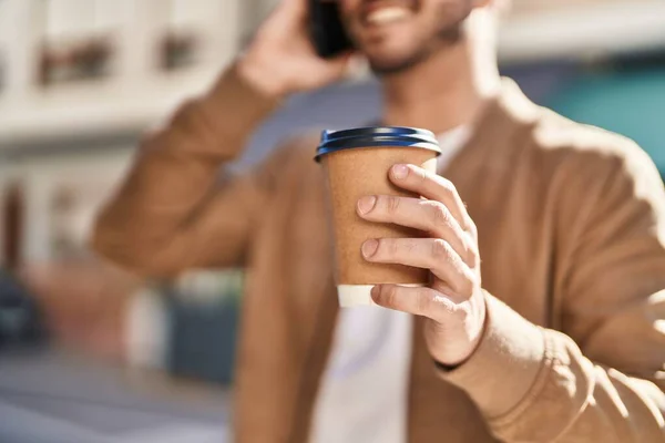 Stock image Young hispanic man talking on the smartphone drinking coffee at street