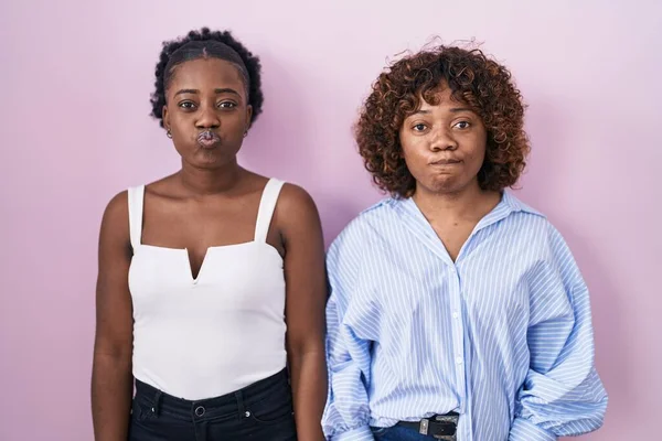 Duas Mulheres Africanas Sobre Fundo Rosa Soprando Bochechas Com Rosto — Fotografia de Stock