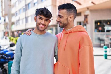 İki erkek caddede birbirlerine sarılıyorlar.