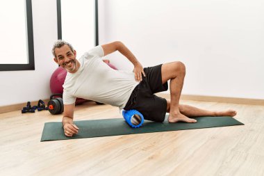 Spor merkezinde gerinirken köpük paten kullanan orta yaşlı, kır saçlı bir adam.