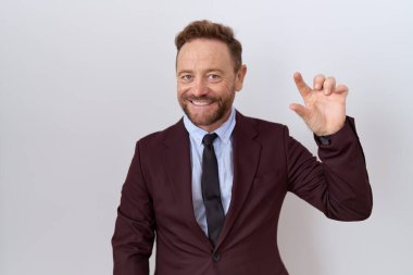 Orta yaşlı iş adamı, sakallı, kravatlı, gülümseyen, kendine güvenen, el hareketi yapan, parmaklarıyla işaret eden ve kameraya bakan. ölçüm kavramı. 