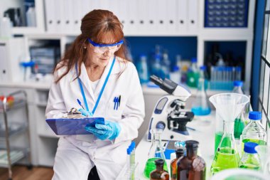 Laboratuvarda panoya yazı yazan orta yaşlı kadın bilim adamı.