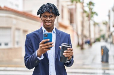 Afro-Amerikalı yönetici akıllı telefon kullanıyor. Sokakta kahve içiyor.