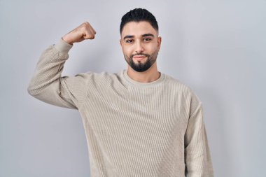 Tecrit edilmiş arka planda duran yakışıklı genç adam güçlü kol kası gösteren, kendinden emin ve gururlu biri. 