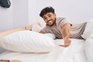 Young arab man smiling confident lying on bed at bedroom