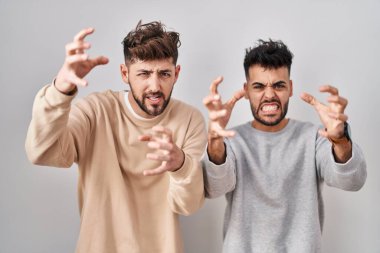 Beyaz arka planda duran genç homoseksüel çift öfkeyle bağırıyor, elleri boğazlamaya çalışıyor, deli gibi bağırıyor. 