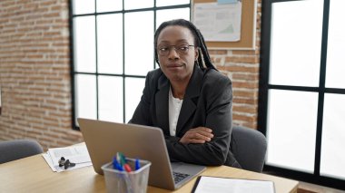 Ofiste çalışırken dizüstü bilgisayar kullanan Afrikalı Amerikalı iş kadını.