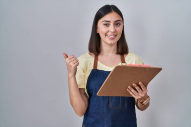 Önlük takan İspanyol kız elinde pano, gülümsüyor mutlu bir şekilde elini ve parmağını yana uzatıyordu. 