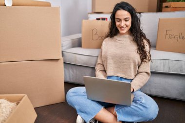 Genç İspanyol kadın yeni evinde dizüstü bilgisayar kullanıyor.