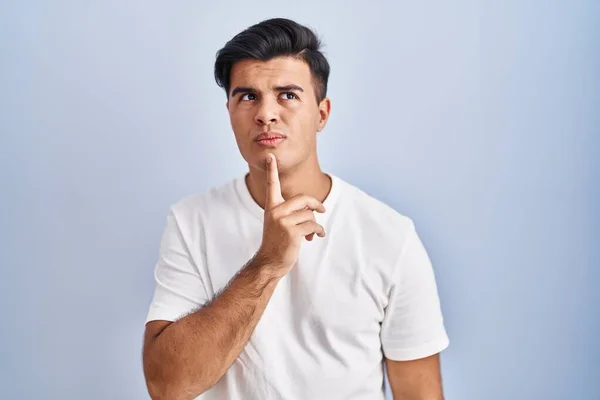 Hispanic Man Standing Blue Background Thinking Concentrated Doubt Finger Chin — 스톡 사진