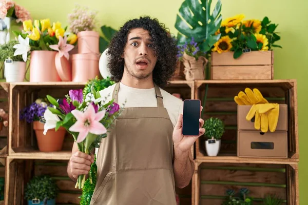리스트 매장에서 일하는 곱슬머리의 스페인 남자가 스마트폰 화면에 충격을 회의적 — 스톡 사진