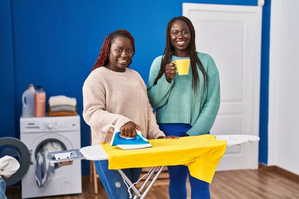 African American Women Ironing Clothes Drinking Coffee Laundry Room — Stock Photo, Image