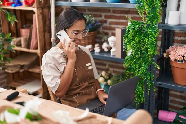 아름다운 히스패닉 리스트가 가게에서 노트북을 사용하는 스마트폰으로 이야기하는 — 스톡 사진
