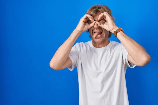 Middle Age Man Standing Blue Background Doing Gesture Binoculars Sticking — Stock Photo, Image