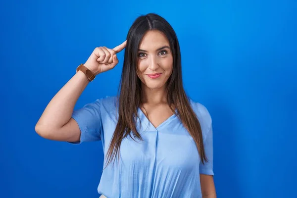 Genç Esmer Kadın Mavi Arka Planda Durup Gülümsüyor Tek Parmağıyla — Stok fotoğraf