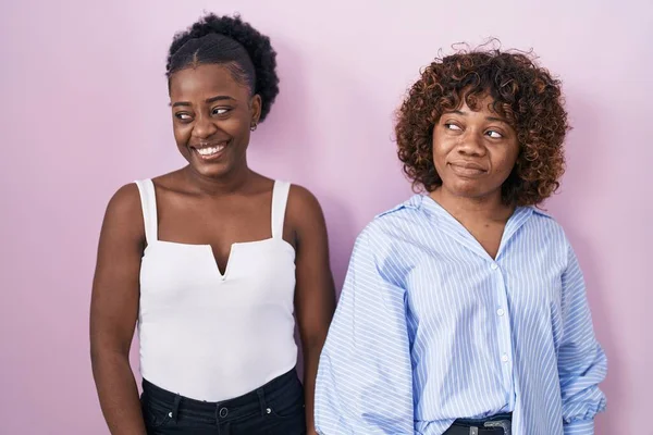 Dos Mujeres Africanas Pie Sobre Fondo Rosa Sonriendo Mirando Hacia —  Fotos de Stock